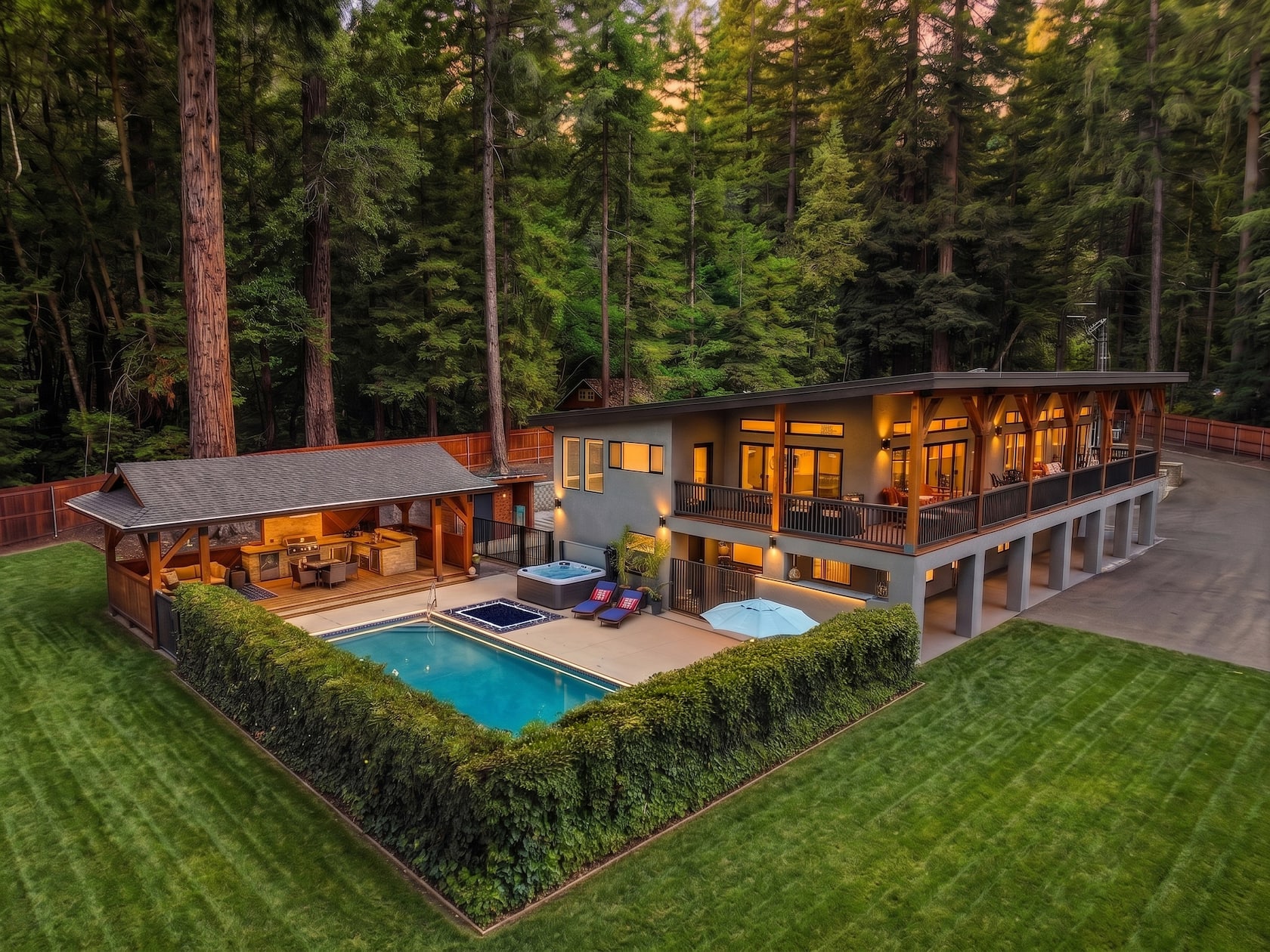 Aerial dusk view of the riverfront estate, pool and cedar cabana surrounded by towering redwoods
